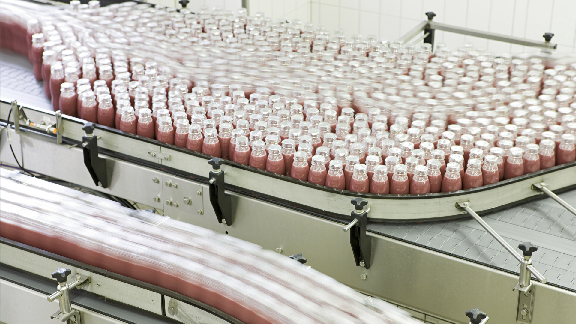 Rows of bottles on a conveyor belt in a bottling factory.