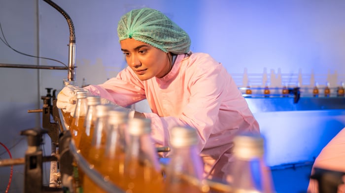 Envato_Woman worker quality control a fruit drink factory in glass. By kelvn_photo_L0