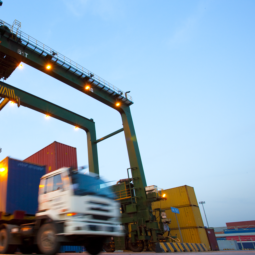 Blurred motion of truck with cargo containers and cranes in a shipping port