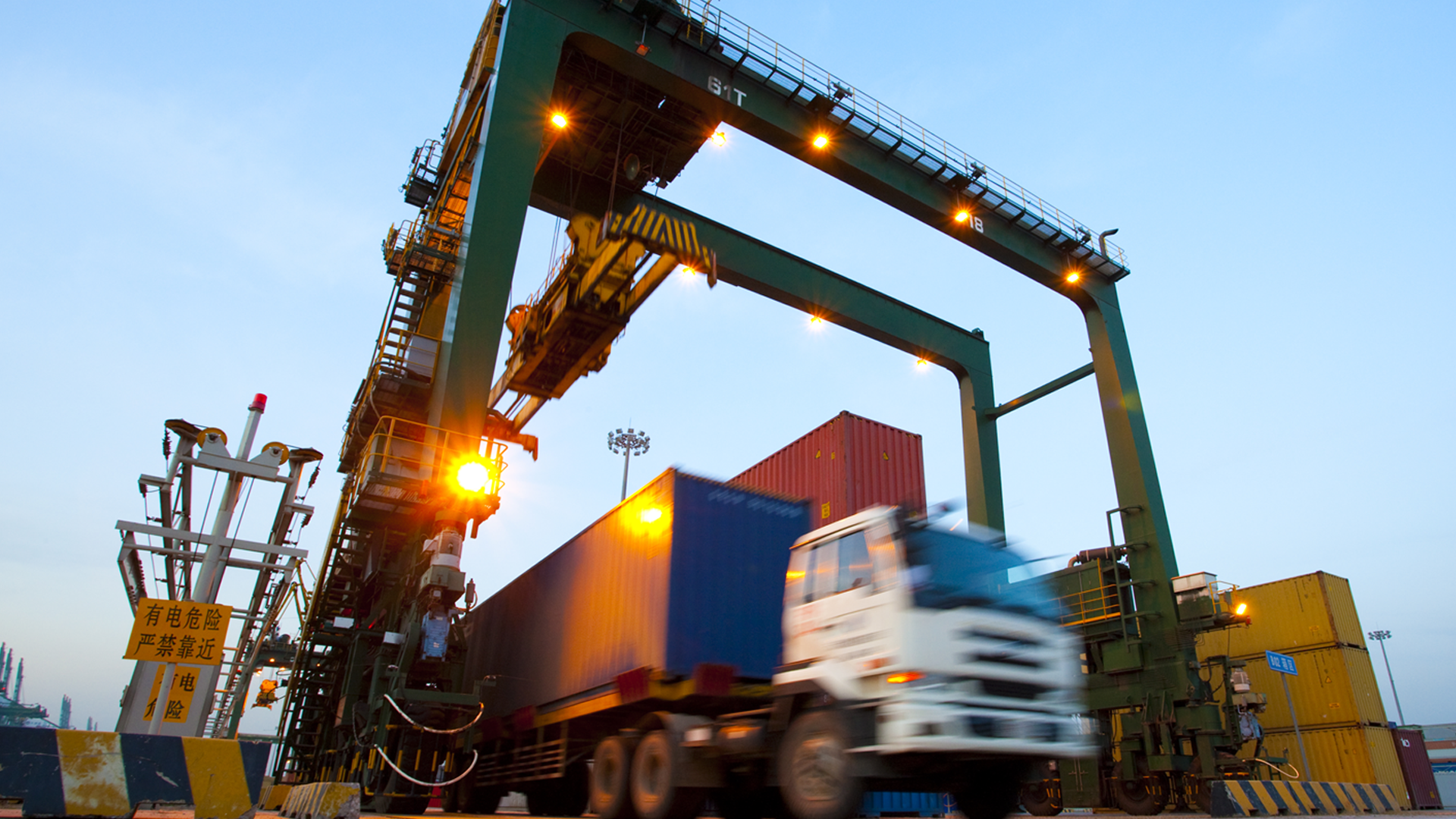 Blurred motion of truck with cargo containers and cranes in a shipping port